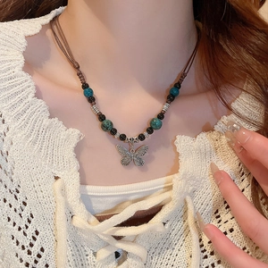 Detail view of a vintage faux leather necklace with silver butterfly pendant and beads