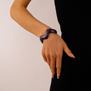 Close-up of wavy acrylic geometric open bangle in translucent purple on woman's wrist