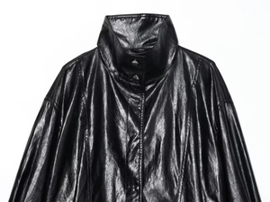 Detailed close-up of glossy black faux leather texture on collar and snap buttons