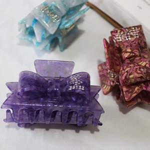 Bow-shaped acetate hair claw clips with rhinestones in purple, blue and pink