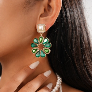 Detail of floral earrings with green teardrop gemstones and white pearl on model