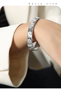 Detailed view of silver flower bracelet with perlée edges on a model wrist