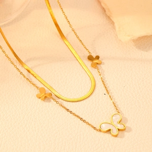 Detail view of gold double layer butterfly necklace on beige leather background
