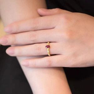 Close-up of vintage gold S925 silver ring featuring an oval red gemstone on the finger