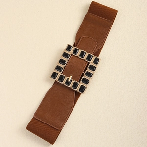 Close-up of brown elastic waist belt with large gold rectangular buckle and black gems