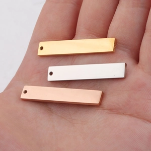 Polished rectangle bar pendants in gold, silver, and rose gold on a palm for size