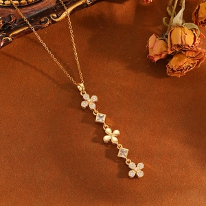 Gros plan d'un collier trèfle doré avec des diamants et un décor floral rétro élégant