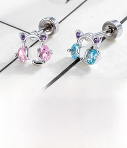Macro detail of cat ear headphone stud earrings in pink and blue zircon with steel posts