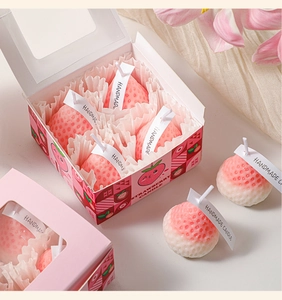 Detailed view of six strawberry-shaped scented candles in a decorative pink gift box