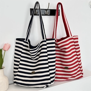 Detail of striped canvas tote bags in navy and red hanging on hooks with a floral backdrop