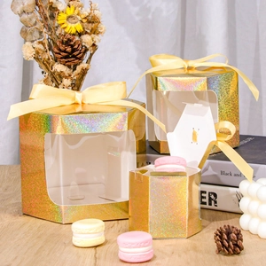 Macro shot of gold laser-cut hexagonal gift boxes with clear windows and ribbons