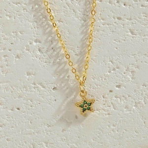 Macro shot of a gold-plated necklace with a vibrant green star-shaped zircon pendant