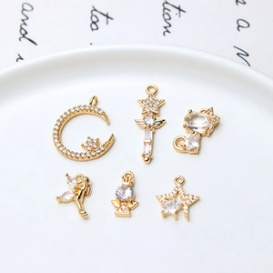 Detailed close-up of golden celestial charms with zirconia inlays on a white ceramic tray