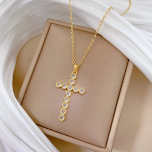 Elegant gold titanium cross pendant necklace with sparkling crystals on silk background
