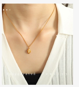 Détail d'un collier avec pendentif ovale doré et petit diamant porté sur le cou d'une femme