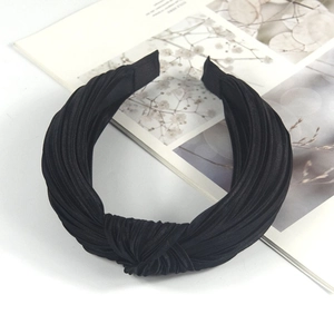 Detail view of the black pleated fabric texture and twisted knot design of the headband