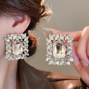 Close-up of model wearing silver square earrings with leaf crystals and large zircon center