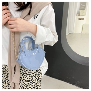Close-up of a mini heart-shaped jelly bag in light blue with a gold chain strap