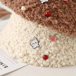Détail du chapeau bob bicolore en polaire avec badge de chat et texture douce en peluche