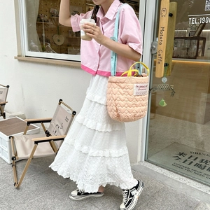 Quilted pink handbag with heart patterns, light blue strap, and yellow handles in a cafe