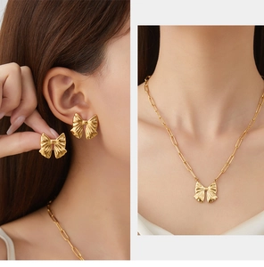 Detail view of gold bow jewelry set with textured metal finish on earrings and necklace
