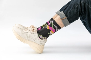 Detail of crew socks with colorful abstract floral patterns and letter print on black cotton