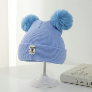 Blue ribbed baby winter hat with double faux fur pom-poms and decorative patch