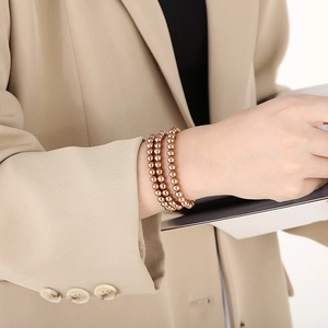Close-up of three-piece rose gold elastic bead bracelets worn on a female wrist