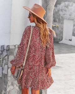 Rear view of a burgundy polka dot long sleeve dress with ruffle hem in a resort setting