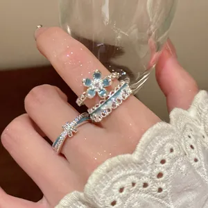Close-up of a three-piece silver flower ring set worn on hand with blue accents
