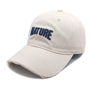 Close-up of beige baseball cap with blue NATURE embroidery and distressed brim details