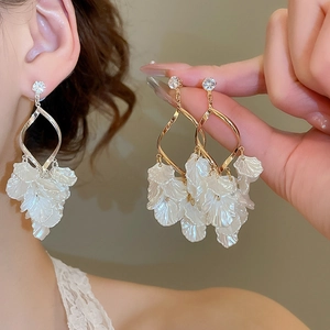Detailed view of gold twisted earrings with zircon studs and white petal-shaped drops