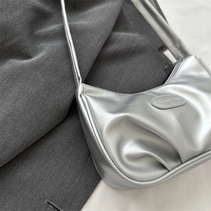 Silver metallic pleated crescent hobo bag for women on grey fabric background