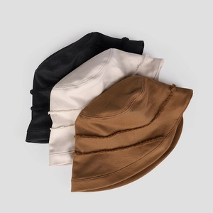 Detail of three cotton bucket hats with vintage frayed edges in black, beige, and tan colors