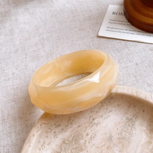 Macro detail of marbled resin bangle featuring geometric faceted design and creamy finish