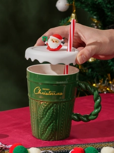 Close-up of hand lifting lid on a green knit texture Christmas mug with Santa topper