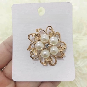 Detailed view of a gold floral brooch with white pearls and sparkling central rhinestone