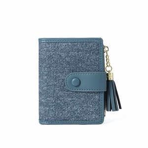 Detail of blue denim textured short wallet with round snap closure and matching fringe tassel