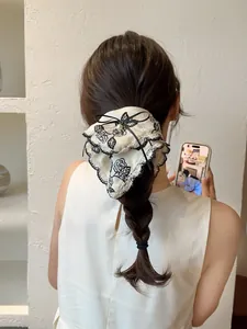 Detail of vintage cream floral hair scrunchie with black lace trim and pearl on a braid