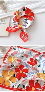 Detailed close-up of a white floral silk scarf featuring vibrant red and orange flower patterns