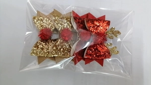 Macro detail of four glitter Christmas antler hair clips with red pom-poms in clear packaging