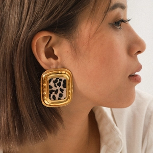 Boucles d'oreilles carrées en acier doré 18K avec motif léopard portées par un mannequin