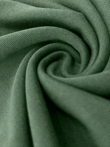 Gros plan du tissu en maille vert foncé montrant la texture côtelée et la grande élasticité