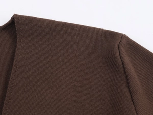 Dettaglio macro della maglia marrone scuro con cuciture sulle spalle e trama fine