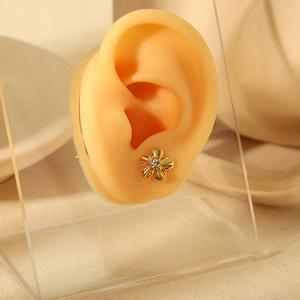 Macro view of 18k gold floral stud earring with textured petals and center crystal