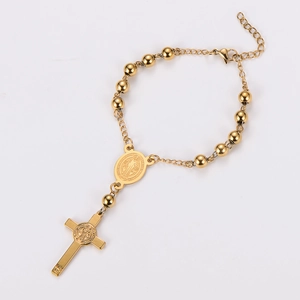 Detail of gold stainless steel rosary bracelet with Saint Benedict medal and cross charm