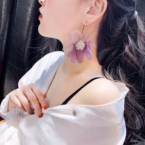 Dettaglio di un grande orecchino a fiore viola con perle e cerchio su modella