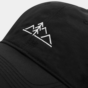 Détail de la broderie blanche de montagne sur une casquette de randonnée noire