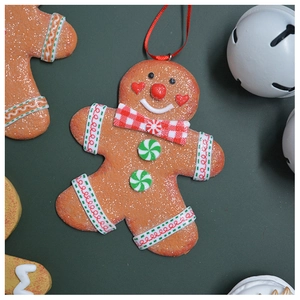 Close-up of a gingerbread man ornament with resin glitter finish and a red ribbon bow