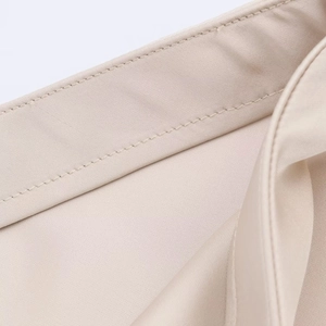 Vue macro détaillée du tissu en satin de dentelle beige montrant la couture et la texture